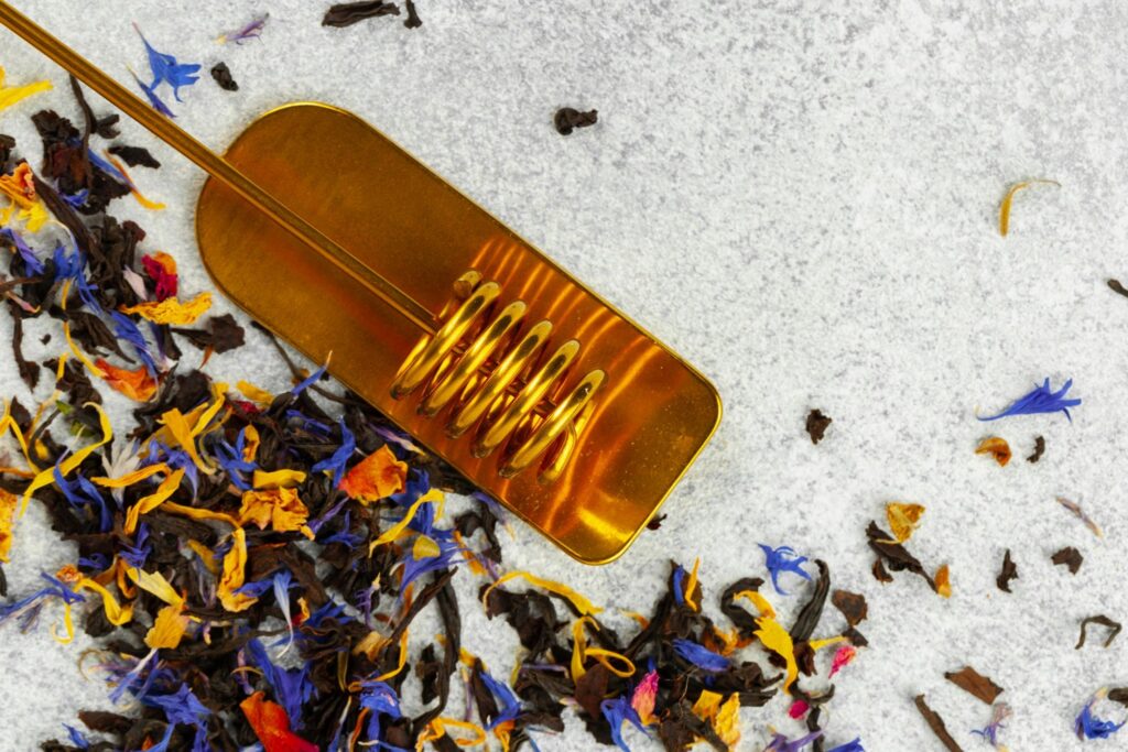 Dry tea keaves with golden spoon close up